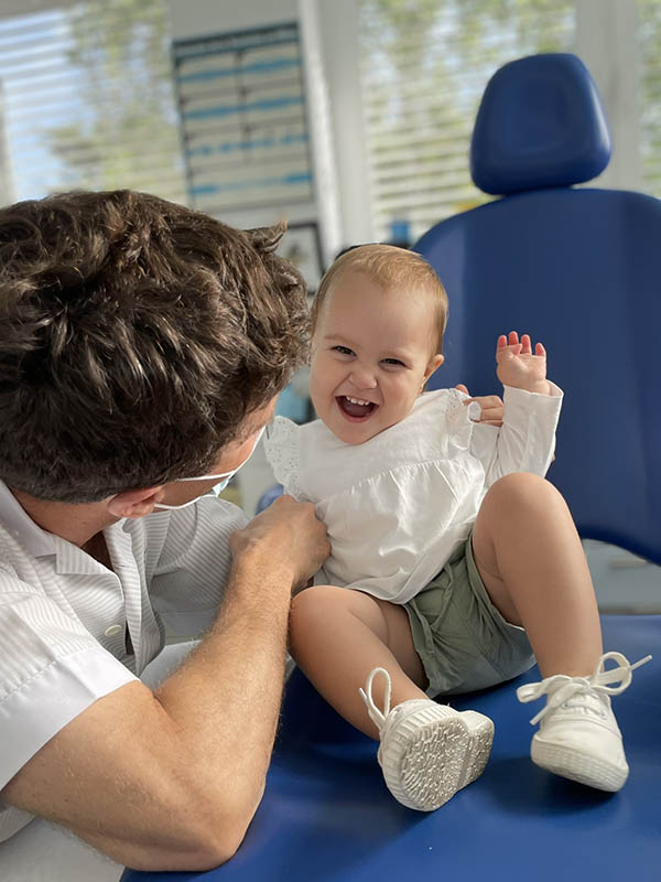 Bebé en consulta riendo e interactuando con su dentista